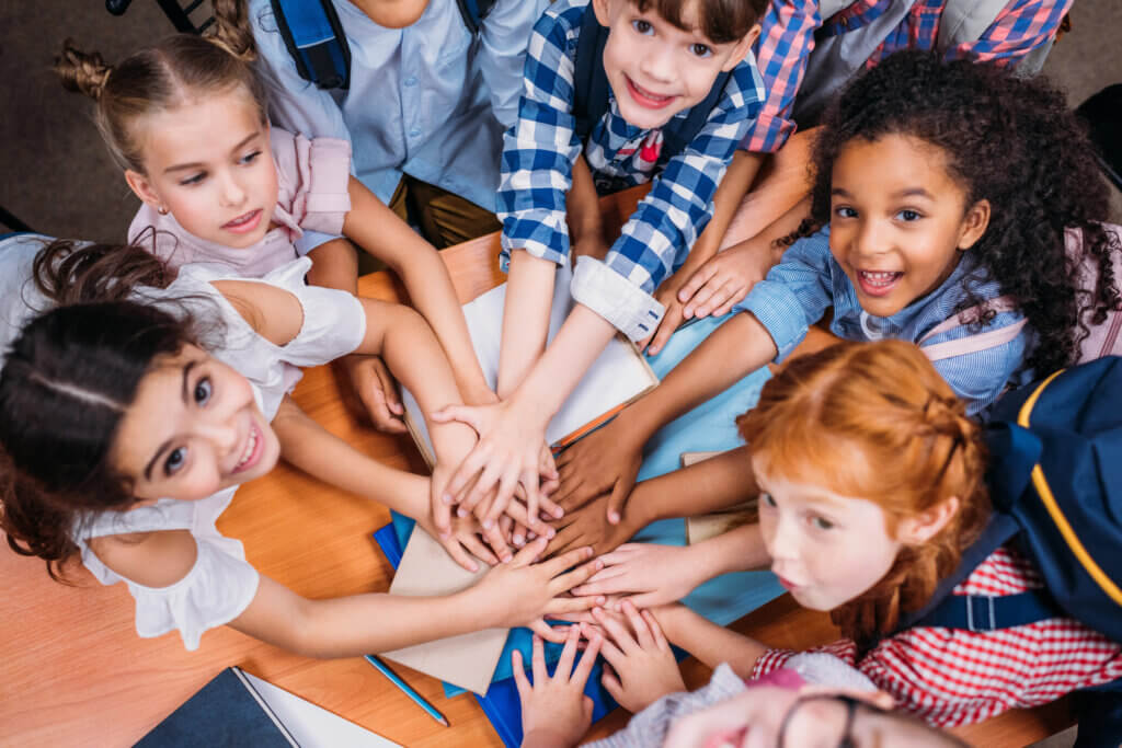 kids in circle with hands on top of each other. 
